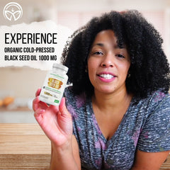 Woman holding a bottle of Mother Nature Organics Organic Cold-Pressed Black Seed Oil Softgels 1000 mg